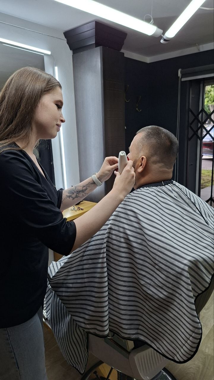 Майстриня підрівнює бороду біля вікна
